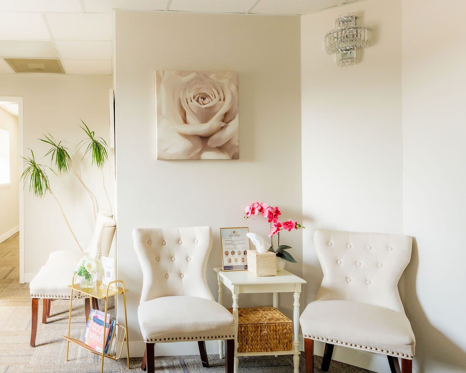 The waiting area with cream chairs, a rose painting, and pink orchids